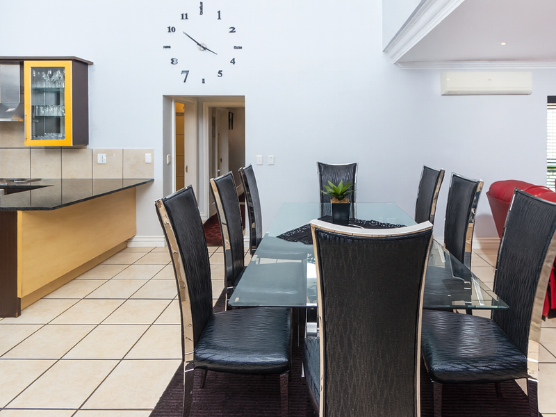 Open-plan living and dining area featuring tiled flooring, a modern kitchen with granite countertops, and a wall-mounted air conditioning unit.