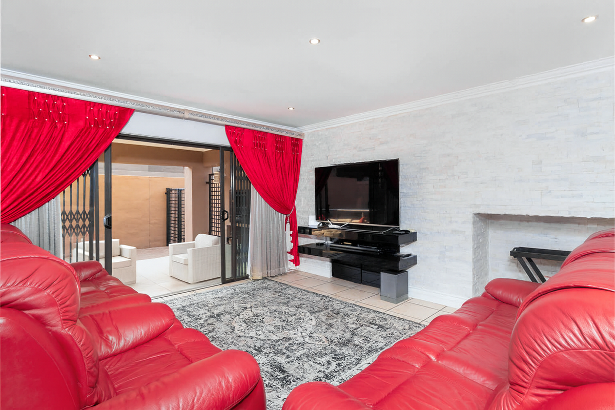 Spacious living room featuring a textured stone feature wall, recessed lighting, and large sliding glass doors providing seamless access to the outdoor patio area.