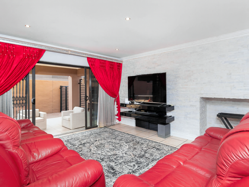 Spacious living room featuring a textured stone feature wall, recessed lighting, and large sliding glass doors providing seamless access to the outdoor patio area.