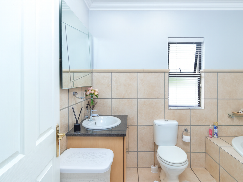 A functional bathroom featuring a vanity with granite countertop, drop-in basin, toilet, and a tiled bathtub surround with neutral wall tiling.