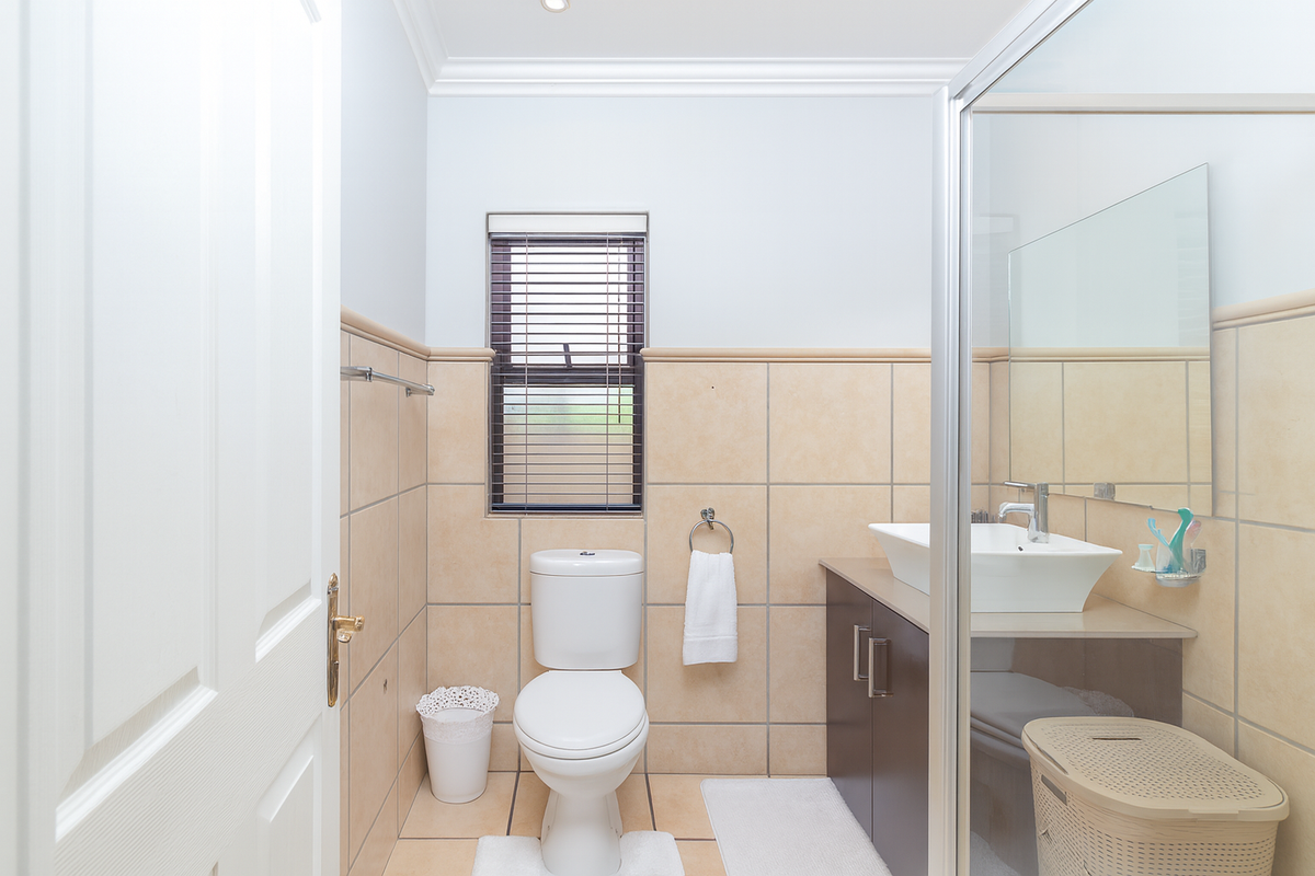 A clean, functional bathroom featuring a vessel sink vanity, a glass-enclosed shower, and neutral wall tiling with a window for natural light.