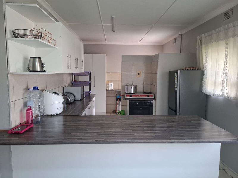 A functional kitchen featuring white cabinetry, dark laminate countertops, a breakfast bar, and a tiled backsplash with a built-in oven.