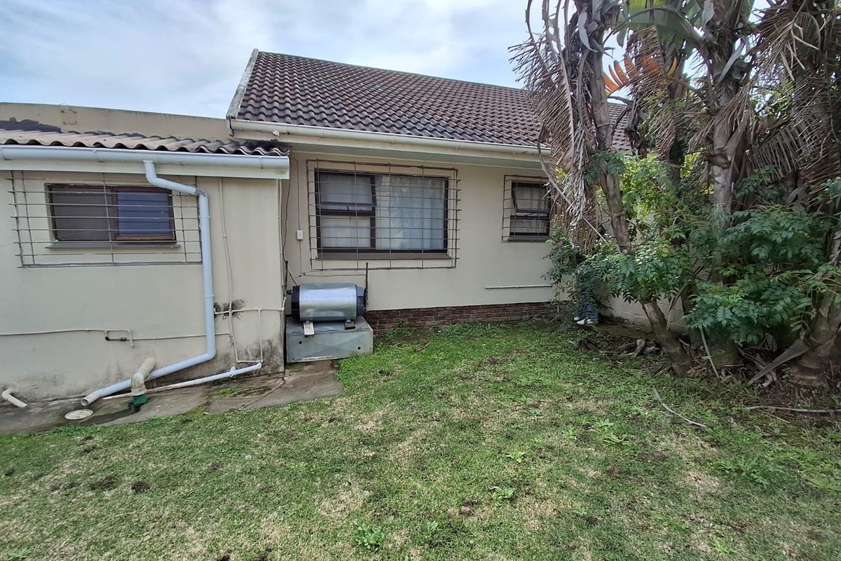 Rear exterior view of the house showing tiled roof, security bars on windows, and an external geyser unit with visible wall staining.