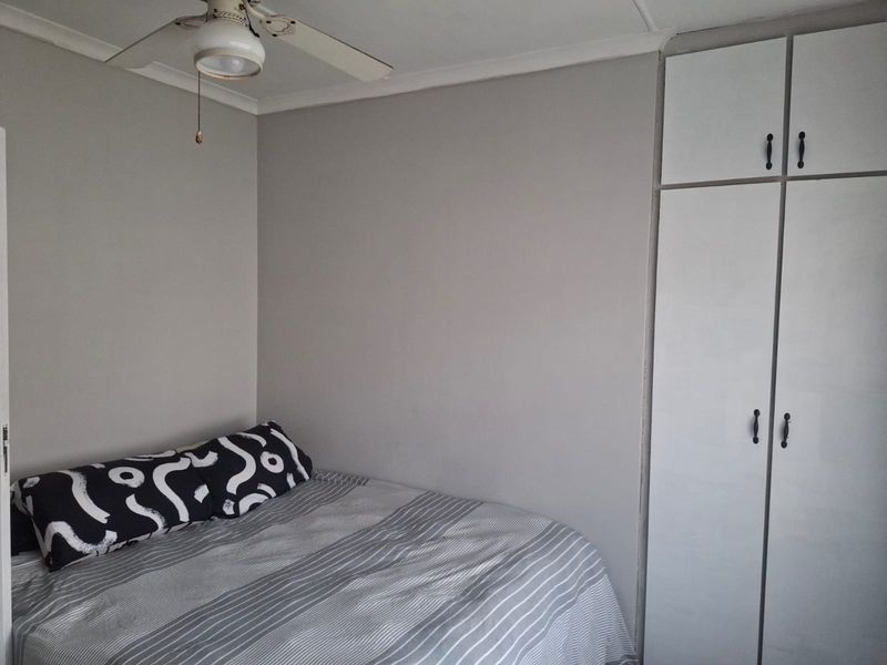 A functional bedroom featuring built-in cupboards and a ceiling fan, providing essential storage and climate control.
