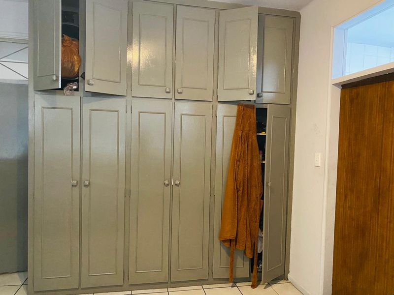 A bedroom featuring floor-to-ceiling built-in cupboards with a painted finish and tiled flooring.
