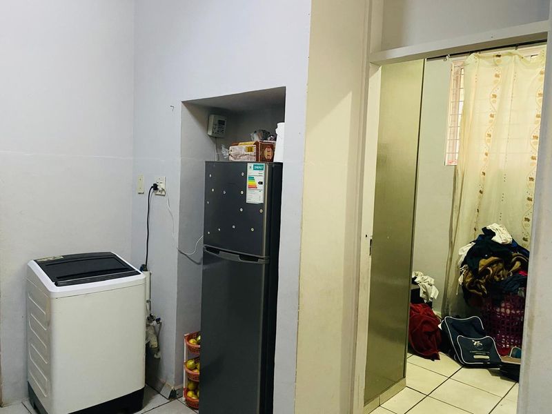 A functional laundry area featuring tiled flooring and a recessed alcove for appliances, requiring minor cosmetic updates to improve the overall finish.