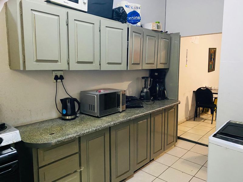 A functional kitchen featuring built-in cabinetry, granite countertops, and tiled flooring, providing a practical workspace with direct access to the adjacent living area.