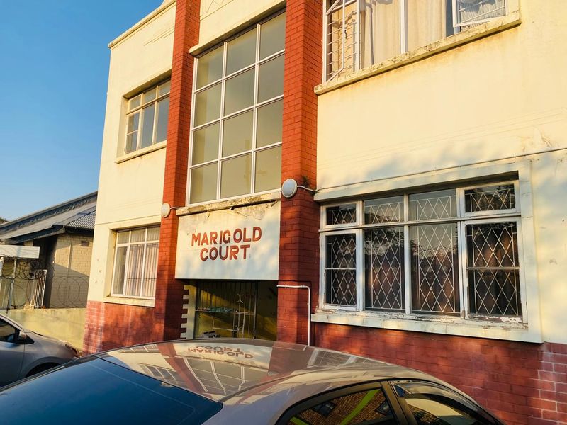 Front elevation of Marigold Court apartment building featuring brick facade detailing and security-barred windows.