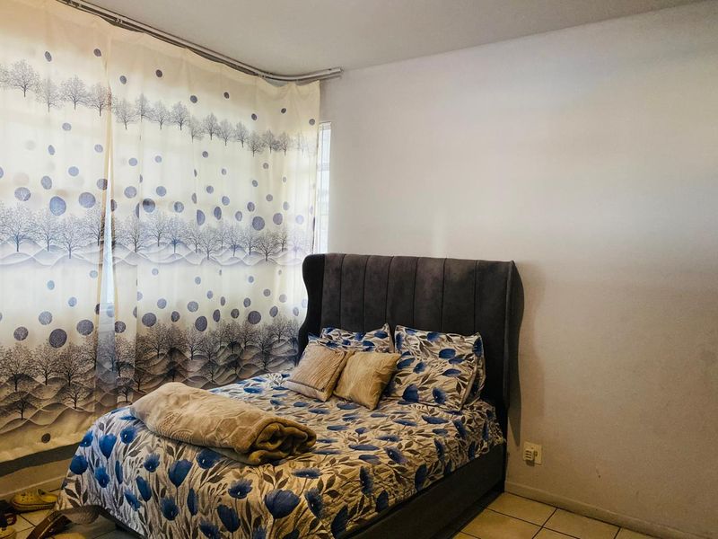 A bedroom featuring tiled flooring and a curtain track, providing a functional space for rest.