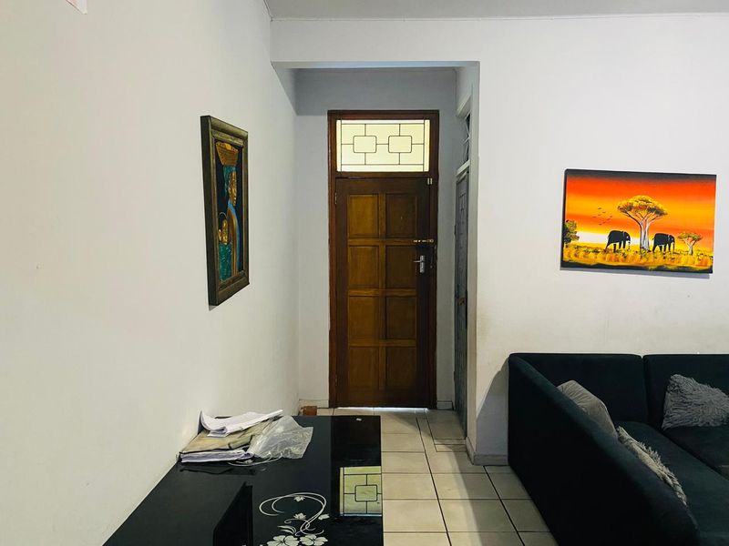 Entrance area featuring a traditional timber panelled front door with a transom window and neutral ceramic floor tiling.