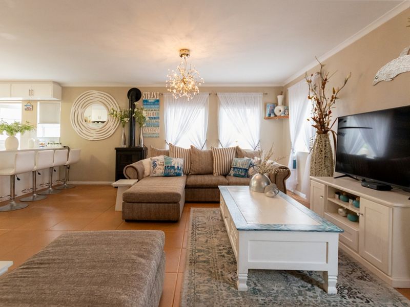 Spacious open-plan living area featuring tiled flooring, a wood-burning stove, and a functional kitchen island, creating a comfortable and integrated home layout.