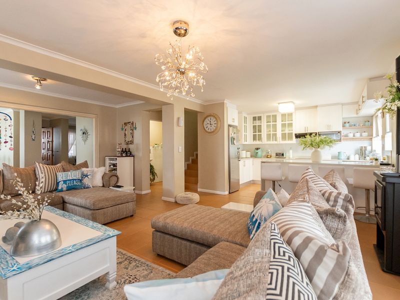 Spacious open-plan living area featuring a modern kitchen with island, tiled flooring, and a cozy wood-burning stove, perfect for family living.