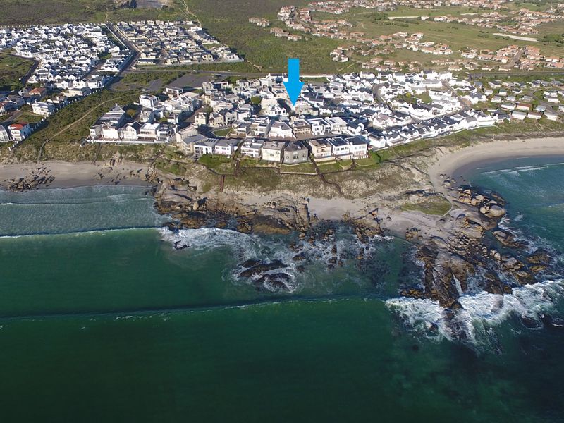 Aerial view of a coastal residential estate situated on a rocky shoreline, highlighting the property's prime location near the ocean.