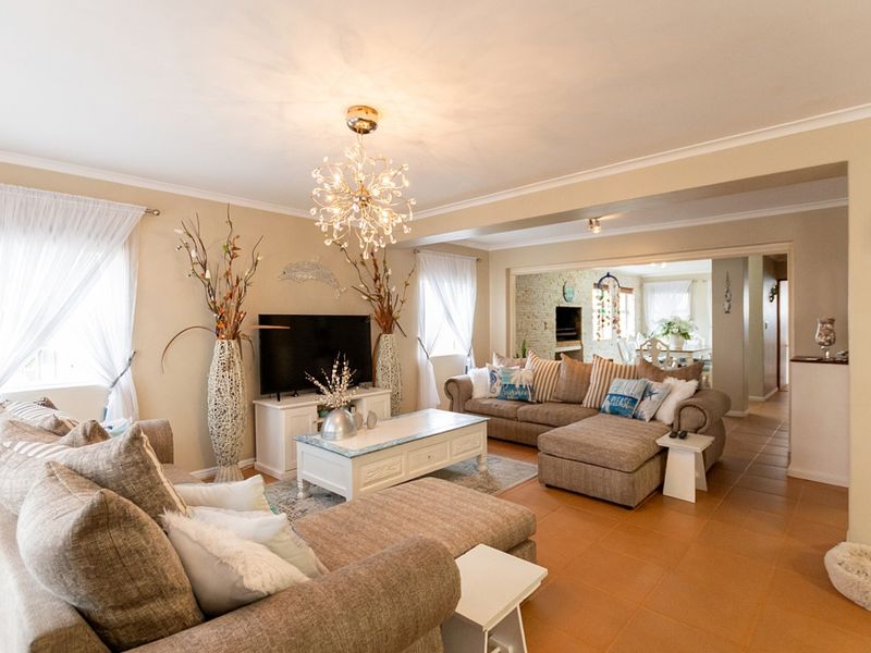 Spacious open-plan living area featuring tiled flooring, decorative chandelier lighting, and seamless flow into the adjacent dining and kitchen space.