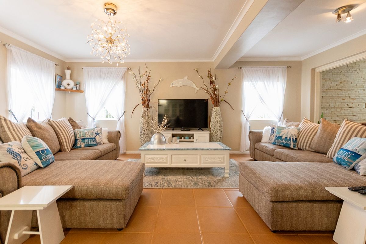A spacious and well-lit living room featuring neutral wall tones, ceramic tile flooring, and elegant ceiling lighting, creating a comfortable and inviting atmosphere.