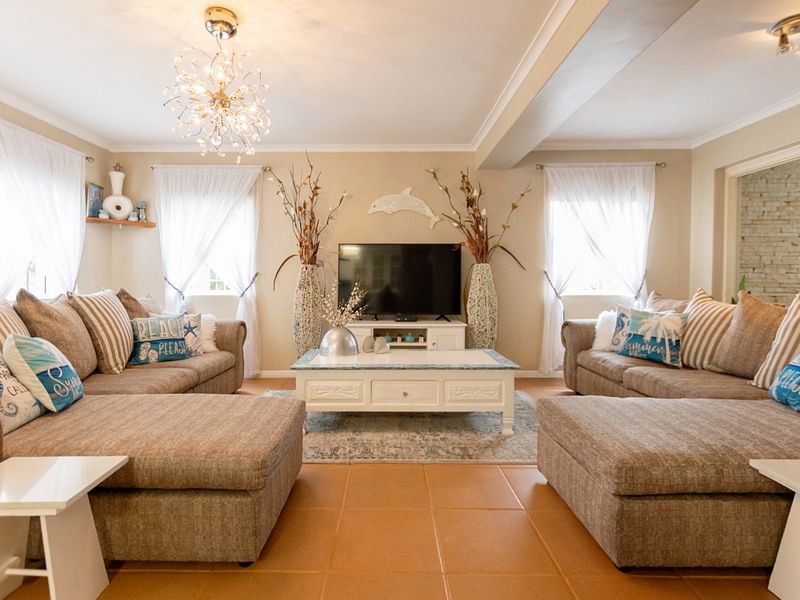 A spacious and well-lit living room featuring neutral wall tones, ceramic tile flooring, and elegant ceiling lighting, creating a comfortable and inviting atmosphere.