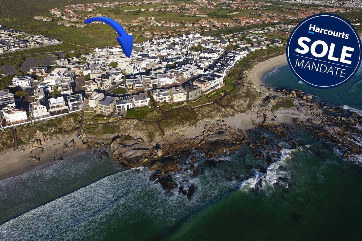 An aerial view of a coastal residential estate situated directly along the shoreline, showcasing the property's prime location and surrounding neighborhood.