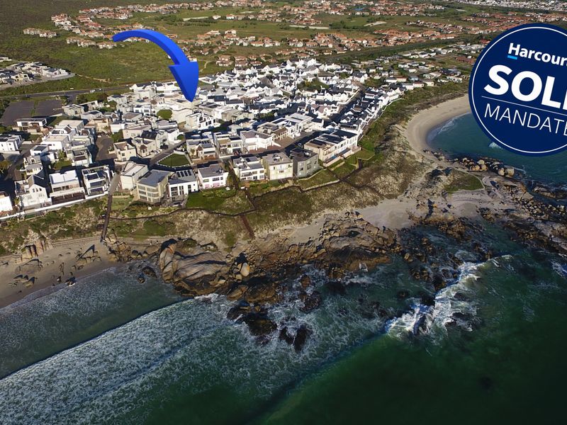 An aerial view of a coastal residential estate situated directly along the shoreline, showcasing the property's prime location and surrounding neighborhood.