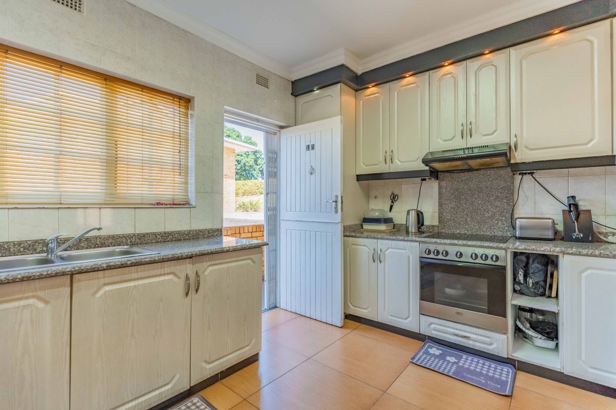 Functional kitchen featuring granite countertops, built-in cabinetry, electric oven with hob, and direct access to the exterior.