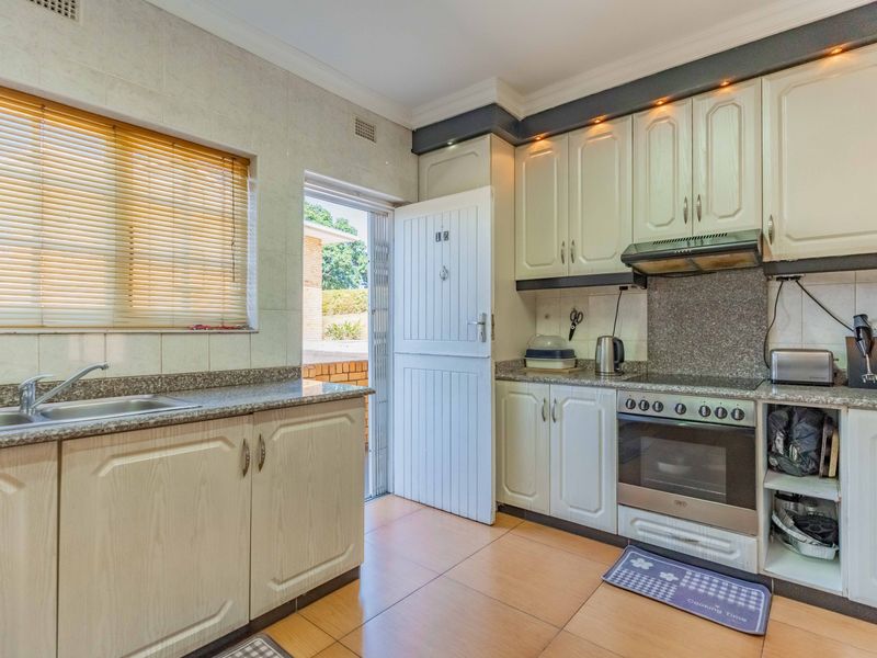 Functional kitchen featuring granite countertops, built-in cabinetry, electric oven with hob, and direct access to the exterior.