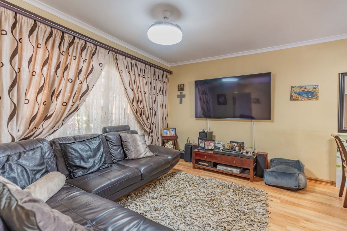 A comfortable living room featuring laminate flooring and a central ceiling light fixture, providing a functional space for relaxation and entertainment.