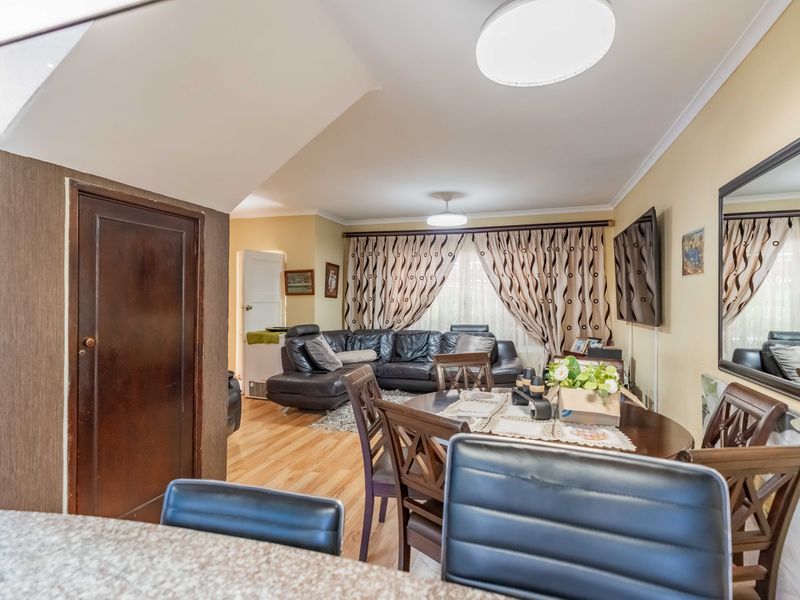 Open plan living and dining area featuring laminate flooring, neutral wall tones, and a functional layout suitable for modern family living.