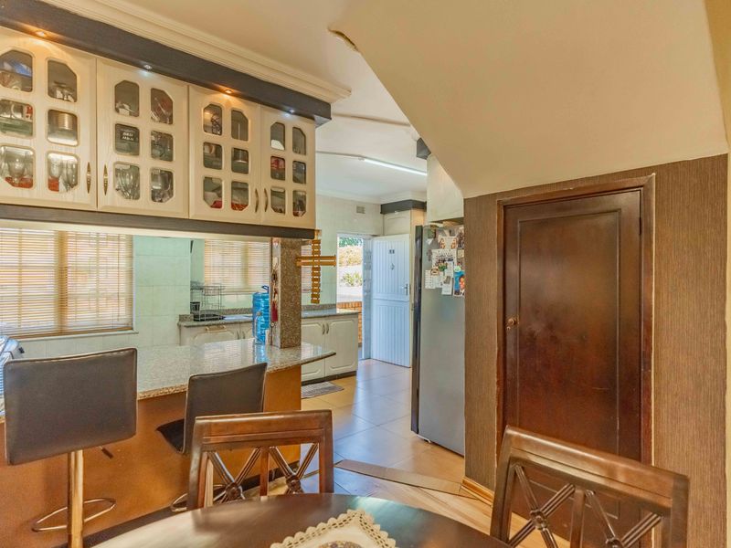 Open plan kitchen and dining area featuring granite countertops, ample built-in cabinetry, and a breakfast bar, connecting to the main living space.