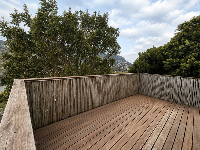 An elevated timber balcony featuring a rustic pole balustrade and scenic mountain views, offering a private outdoor space.