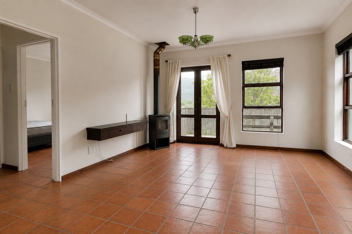 Spacious living room featuring terracotta floor tiles, a freestanding fireplace, and direct access to the outdoor area through french doors.