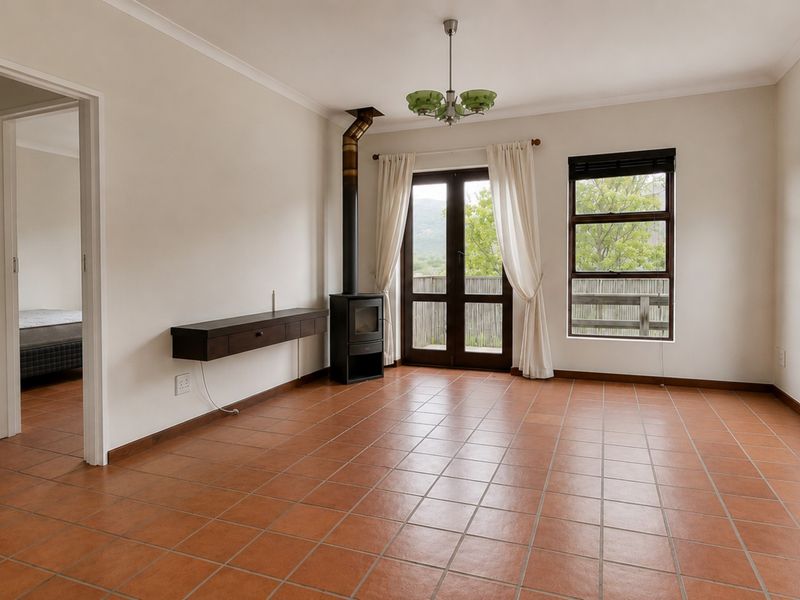 Spacious living room featuring terracotta floor tiles, a freestanding fireplace, and direct access to the outdoor area through french doors.
