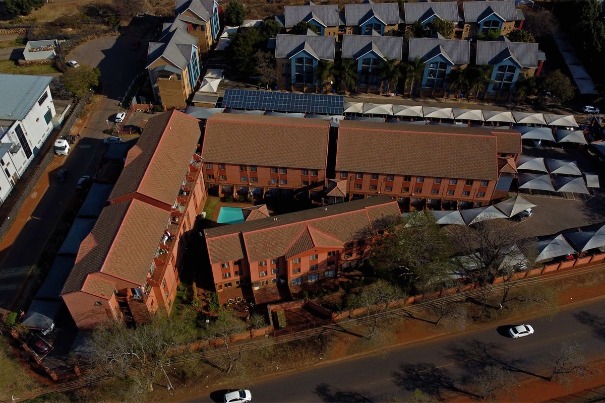 Aerial view of a residential apartment complex featuring multiple brick buildings, a swimming pool, and covered parking areas.