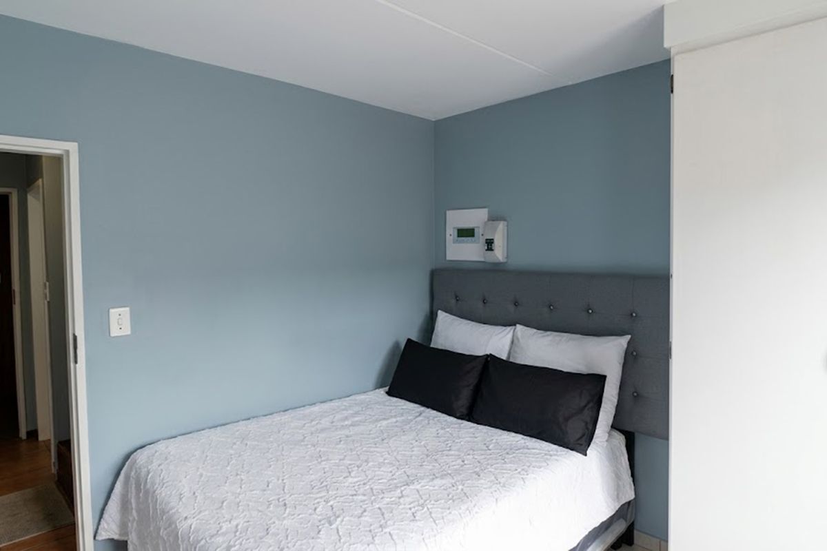 A well-maintained bedroom featuring blue accent walls, a built-in wardrobe, and a wall-mounted electrical distribution board.