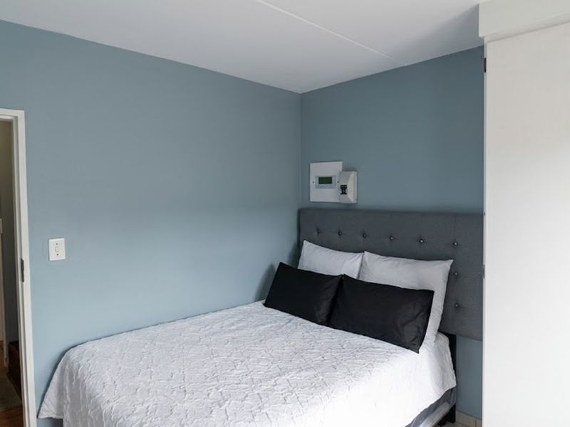 A well-maintained bedroom featuring blue accent walls, a built-in wardrobe, and a wall-mounted electrical distribution board.