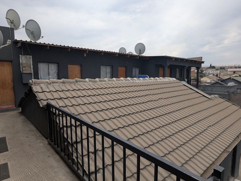 Exterior view of the apartment building featuring a tiled roof, metal balustrades, and multiple satellite dish installations.