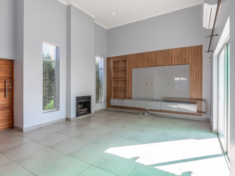 Spacious living room featuring modern tiled floors, a built-in fireplace, and custom timber slat wall paneling with integrated media cabinetry.