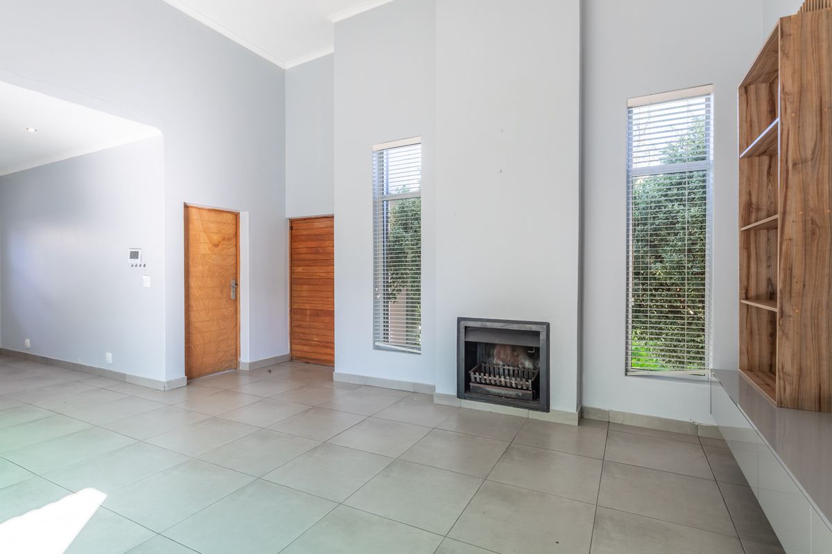 Spacious living room featuring high ceilings, tiled flooring, a built-in fireplace, and custom shelving, offering a bright and neutral canvas for interior design.