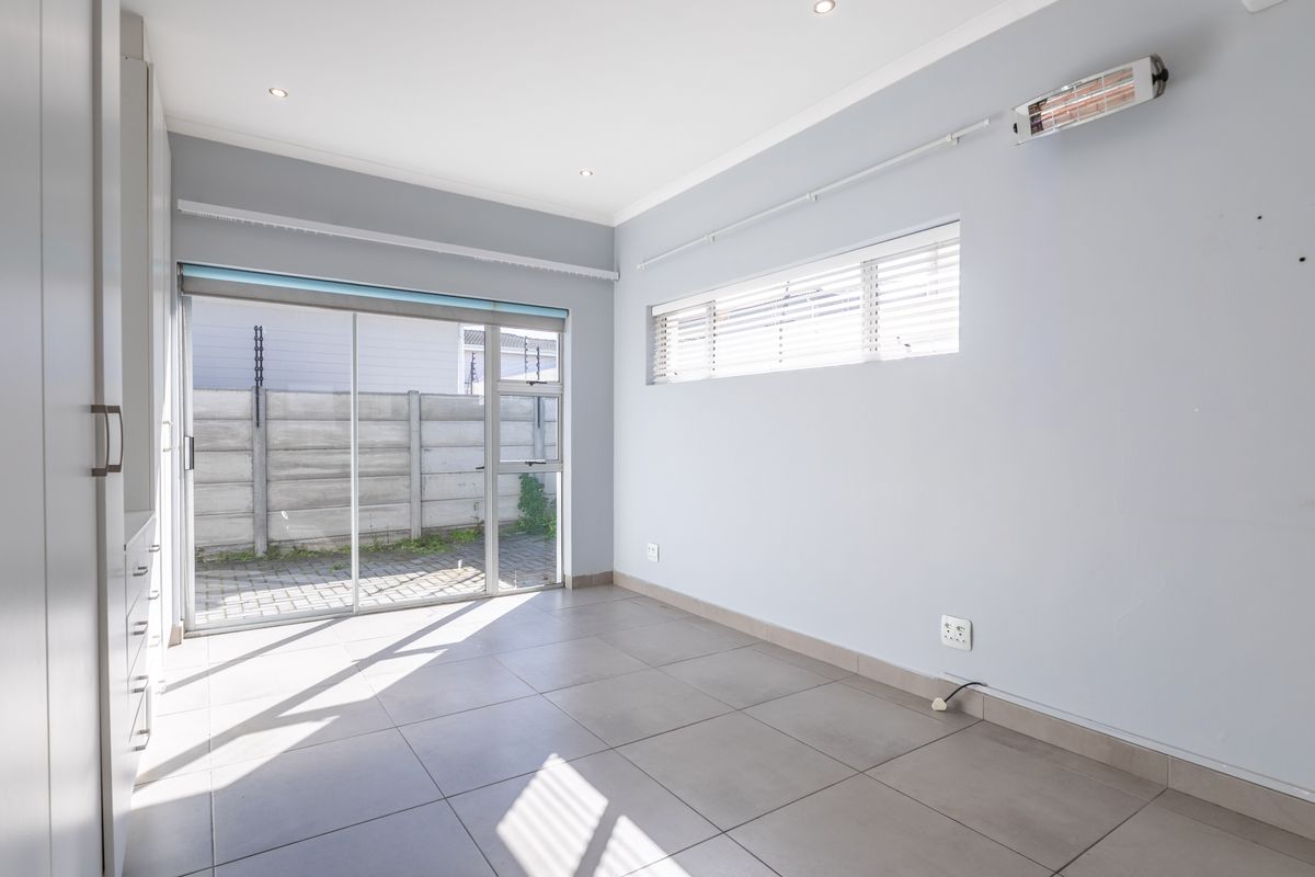 A bright, empty bedroom featuring tiled flooring, built-in cupboards, and a sliding glass door providing direct access to the exterior.