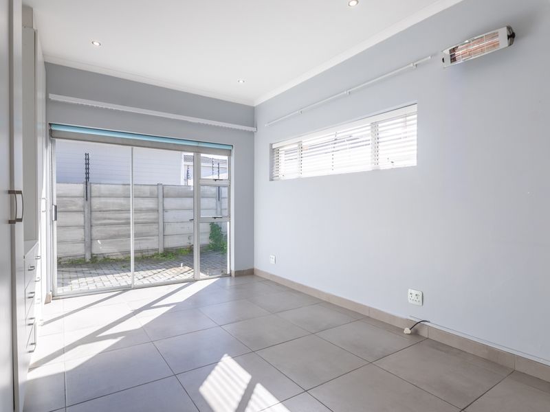 A bright, empty bedroom featuring tiled flooring, built-in cupboards, and a sliding glass door providing direct access to the exterior.