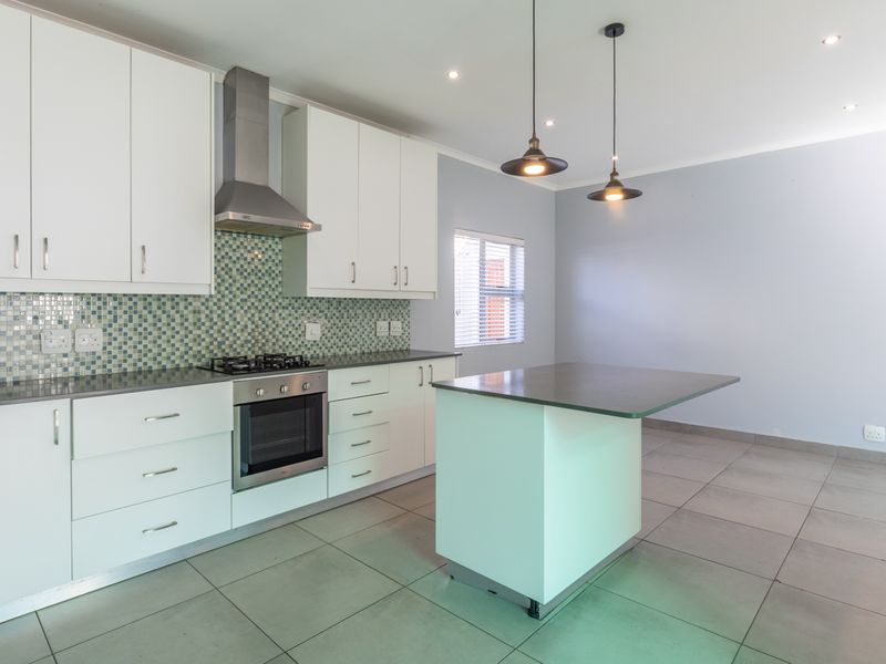 Modern kitchen featuring white cabinetry, a mosaic tile backsplash, stainless steel appliances, a central island, and neutral tiled flooring in an open-plan layout.