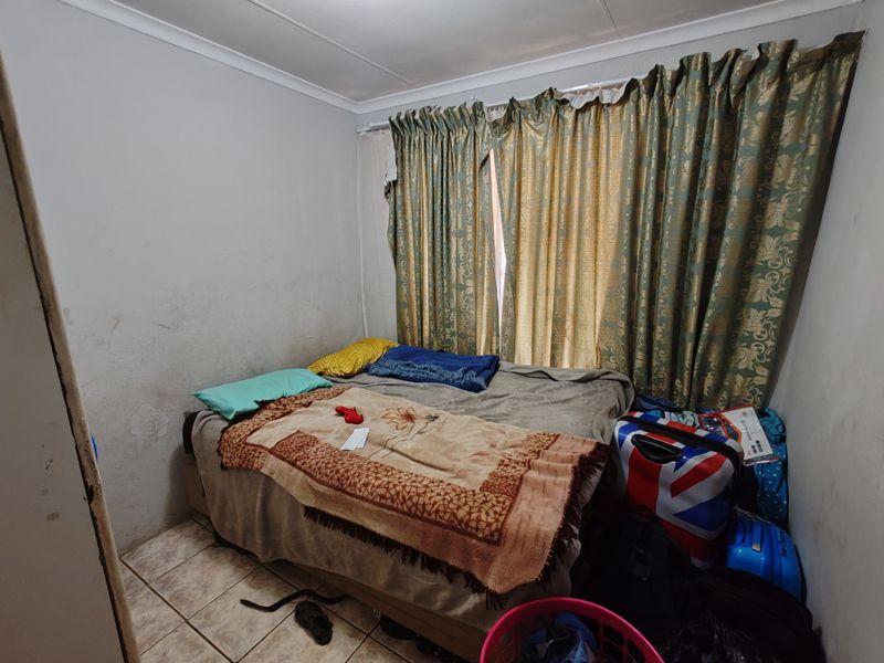 A compact bedroom featuring tiled flooring and coved ceilings, currently requiring cosmetic updates to the wall finishes.