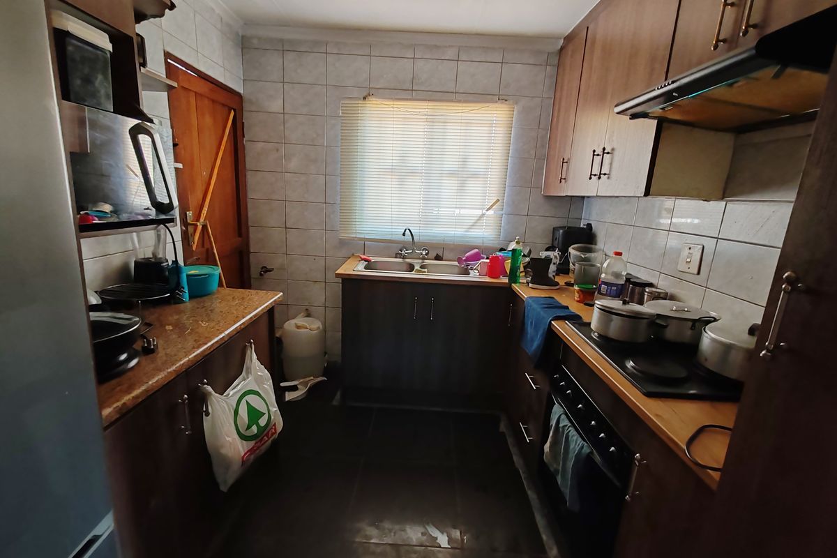 A functional kitchen featuring built-in wooden cabinetry, a double sink, and integrated cooking appliances with tiled splashbacks.