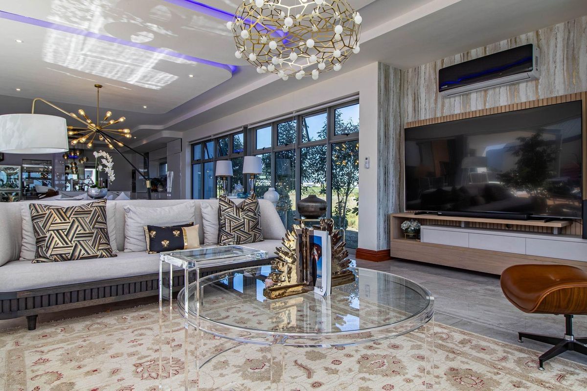 Modern, well-appointed living room featuring recessed ceiling lighting, LED cove accents, large aluminium windows, and a sleek built-in media console.