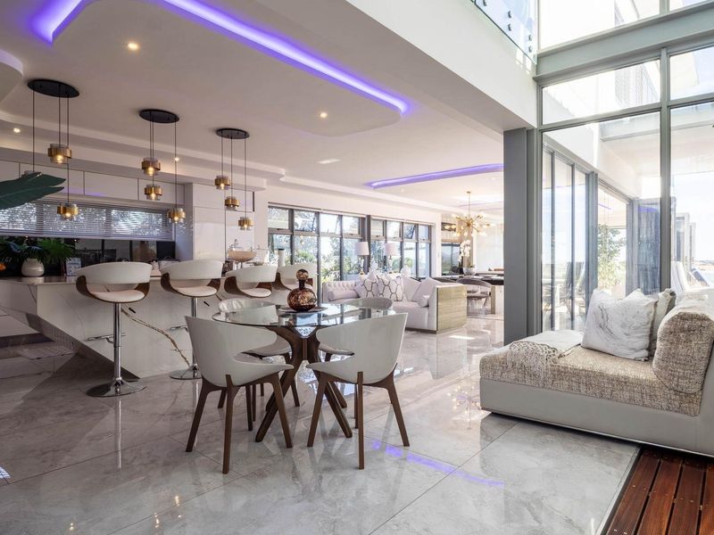 Spacious open-plan living and kitchen area featuring high-end finishes, recessed LED ceiling lighting, large format floor tiles, and expansive floor-to-ceiling glass doors.