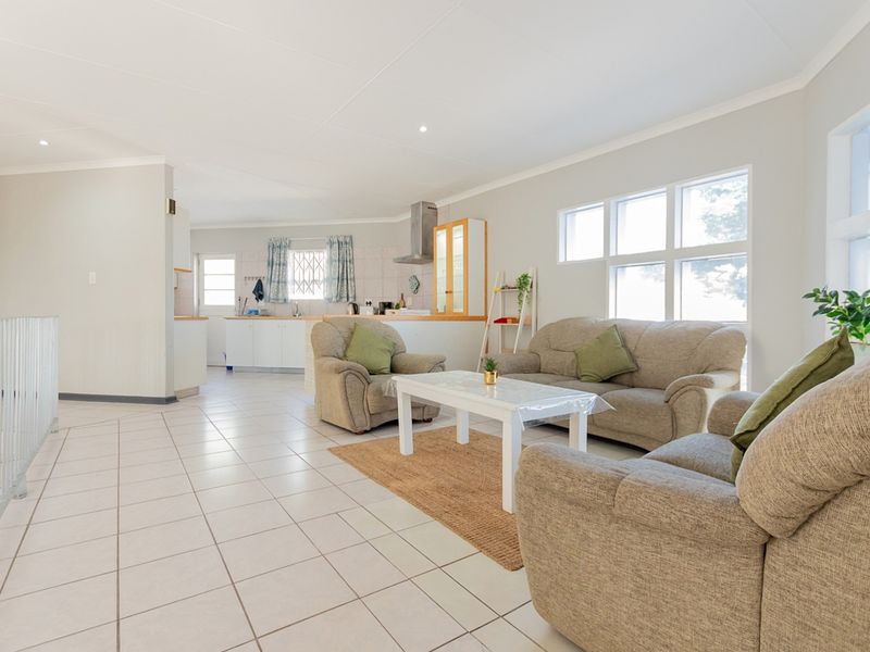 Spacious open-plan living area featuring tiled flooring, recessed lighting, and a functional kitchen with built-in cabinetry and a stainless steel extractor fan.