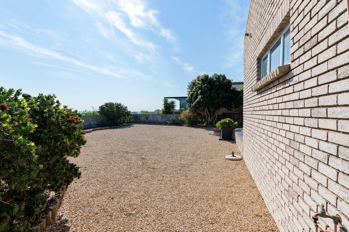 A low-maintenance rear exterior area featuring a gravel surface, brick wall facade, and boundary wall, providing a clean and functional outdoor space.