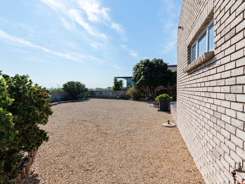 A low-maintenance rear exterior area featuring a gravel surface, brick wall facade, and boundary wall, providing a clean and functional outdoor space.