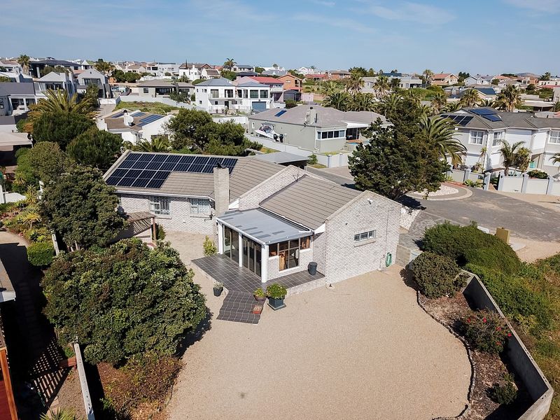 Aerial view of a residential property featuring a brick exterior, tiled roof with solar panels, and a covered patio area.