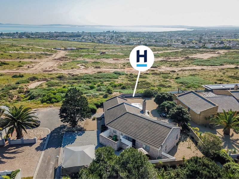 Aerial view of a residential property featuring a tiled roof, brick chimney, and surrounding landscaped grounds with coastal views in the distance.