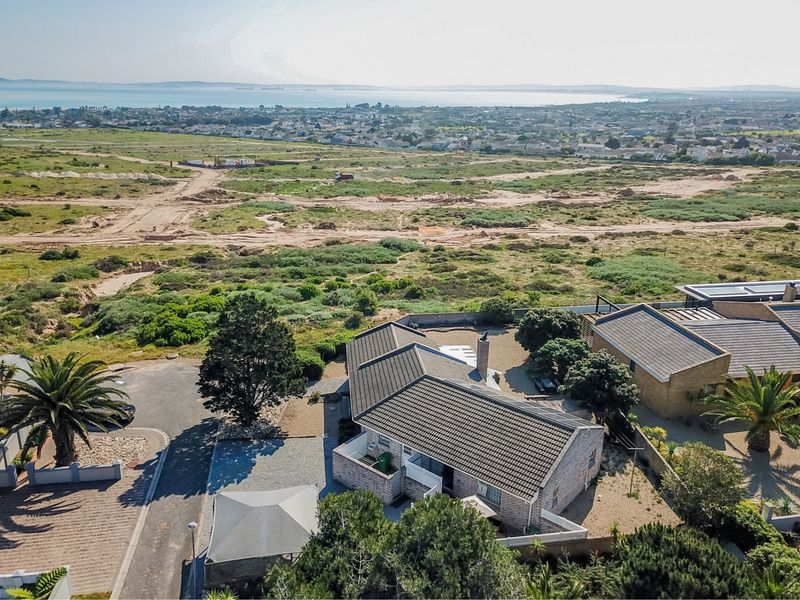 Aerial view of the property showcasing the roof structure, driveway, and surrounding landscape with distant coastal views.