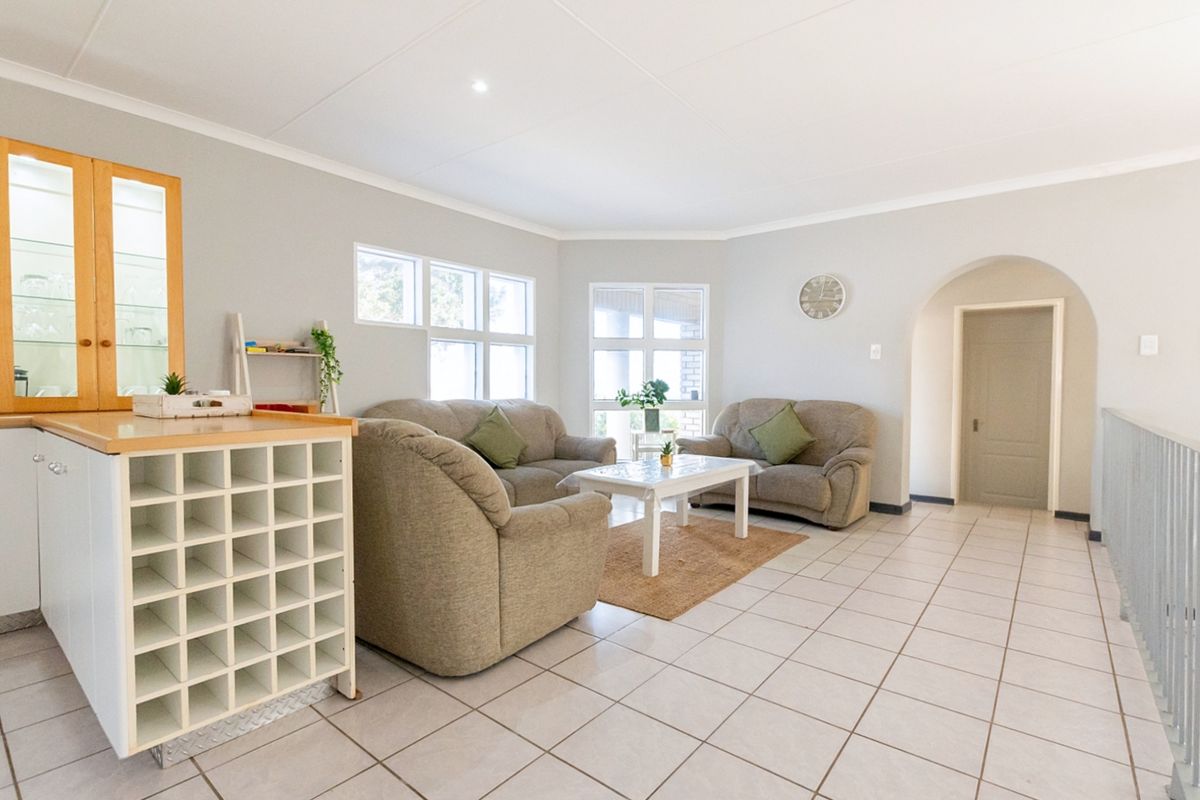 A bright, open-plan living area featuring neutral tiled flooring, a distinctive arched doorway, and a built-in wine rack with integrated cabinetry.